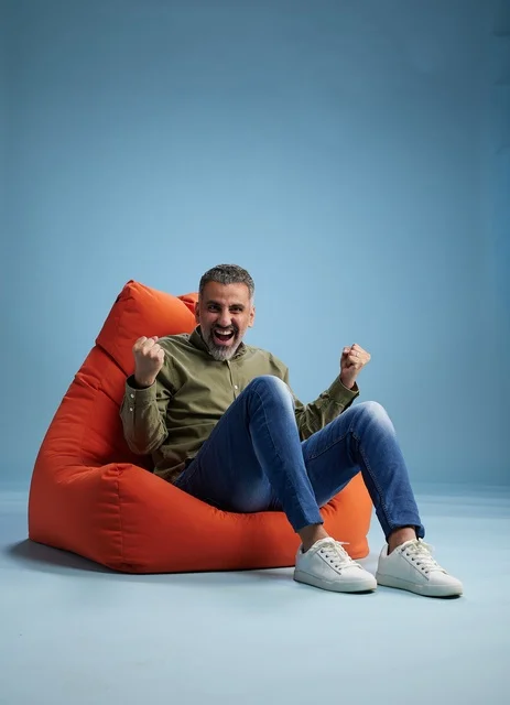 Excited Man Celebrating on Orange Beanbag Chair