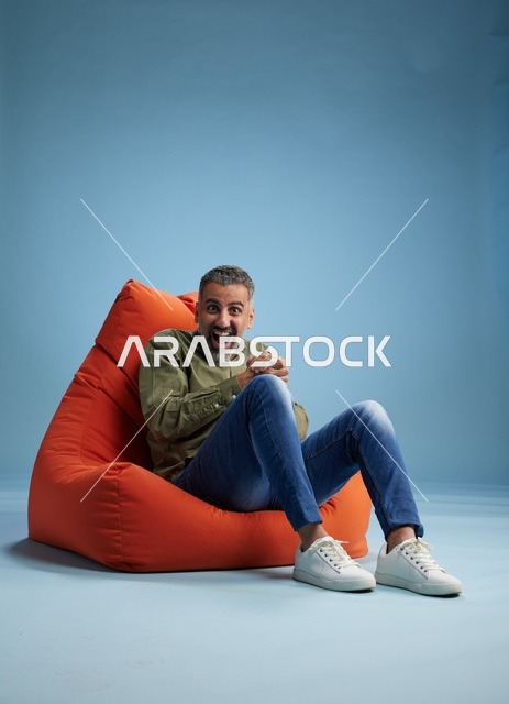 رجل متحمس يجلس على كرسي بين باج برتقالي