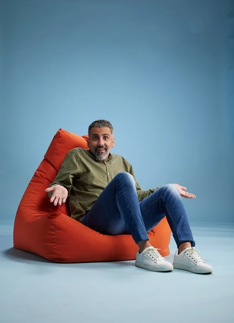 Surprised Man Sitting on Orange Bean Bag in Studio