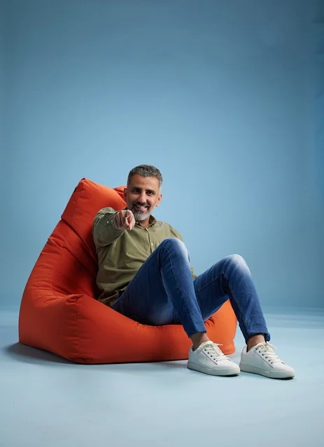 Arab Man Pointing from Orange Bean Bag Chair