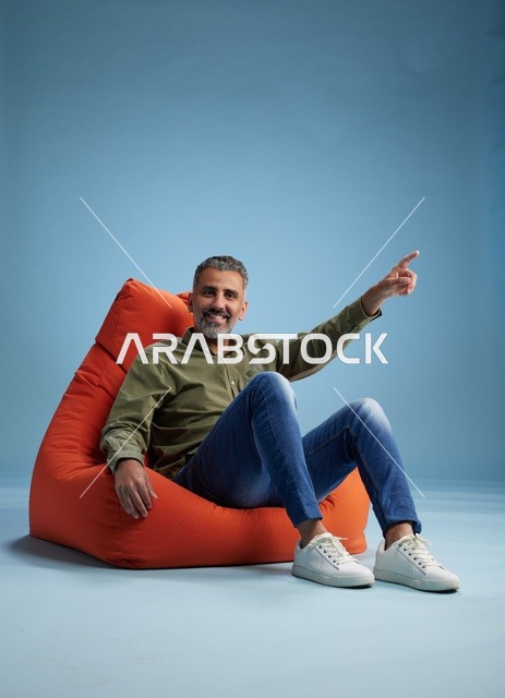 Smiling Arab Man Pointing on Orange Beanbag Chair