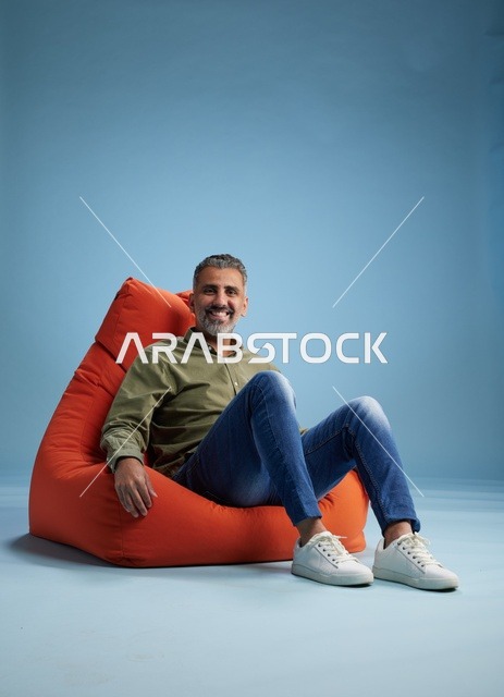 رجل عربي يجلس على كرسي بين باج في استوديو