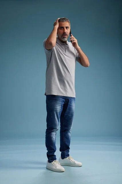 رجل سعودي يتحدث على الهاتف بتعبير وجه مصدوم