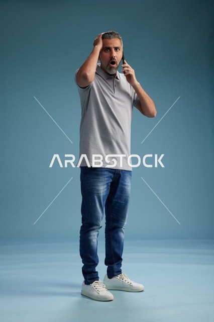 رجل سعودي مصدوم يتحدث بالهاتف خلفية زرقاء