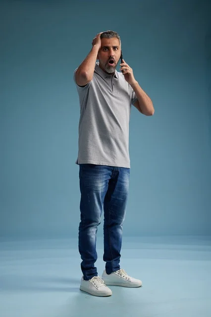 رجل سعودي مصدوم يتحدث بالهاتف خلفية زرقاء