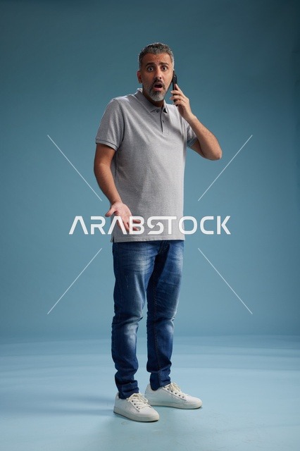 رجل سعودي يتحدث بالهاتف بتعبيرات وجه مصدومة