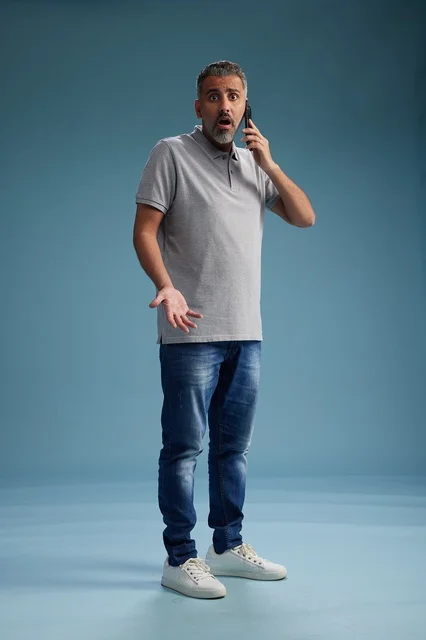 رجل سعودي يتحدث بالهاتف بتعبيرات وجه مصدومة