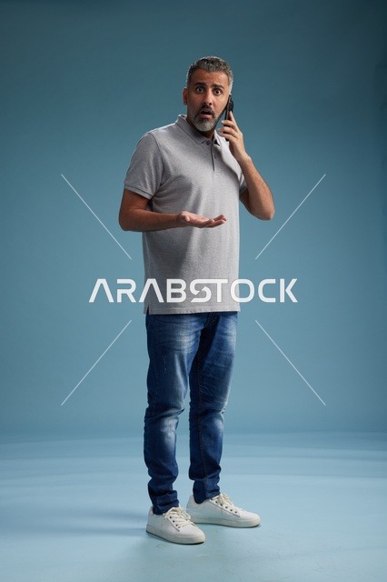 رجل سعودي يتحدث على الهاتف بتعبير وجه مصدوم