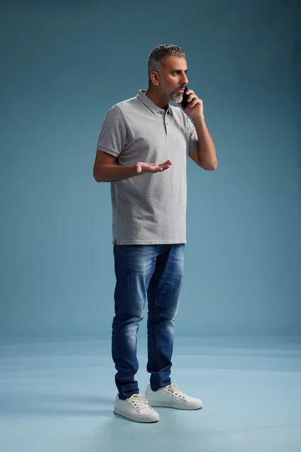 رجل سعودي بملابس كاجوال يتحدث بالهاتف المحمول