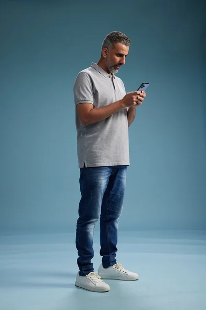 Arab Man Using Smartphone on Blue Studio Background