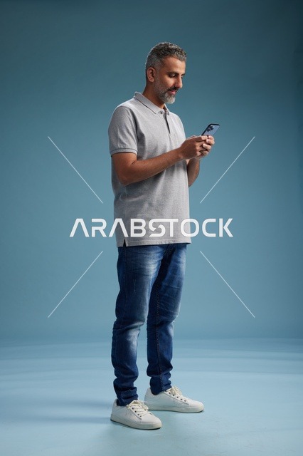Middle-aged Arab Man Using Smartphone on Blue Background