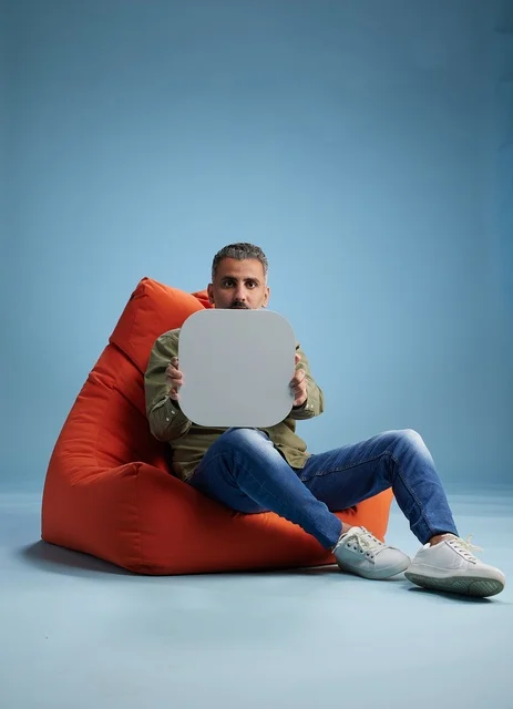 رجل سعودي يجلس على مقعد برتقالي يحمل لافتة فارغة