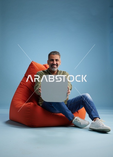 رجل سعودي يحمل لافتة فارغة على مقعد برتقالي