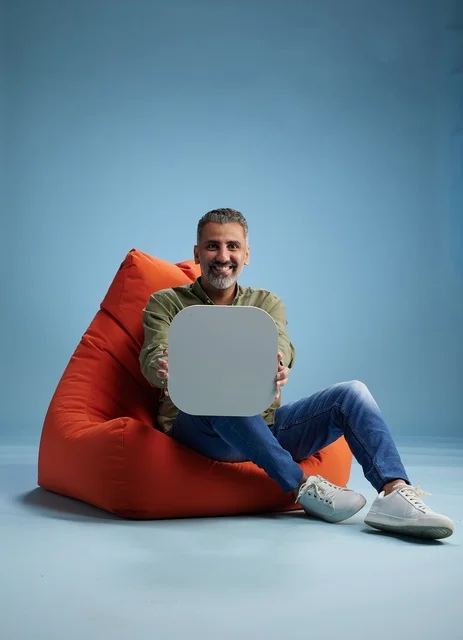 رجل سعودي يحمل لافتة فارغة على مقعد برتقالي