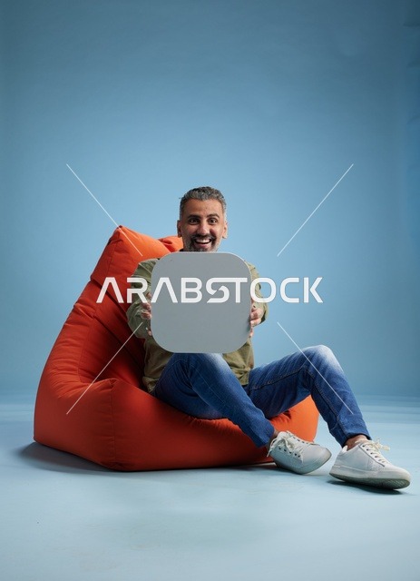 رجل سعودي على مقعد استرخاء يحمل لوحة إعلانية فارغة