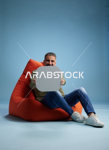 رجل سعودي على كرسي بين باج يحمل لافتة فارغة