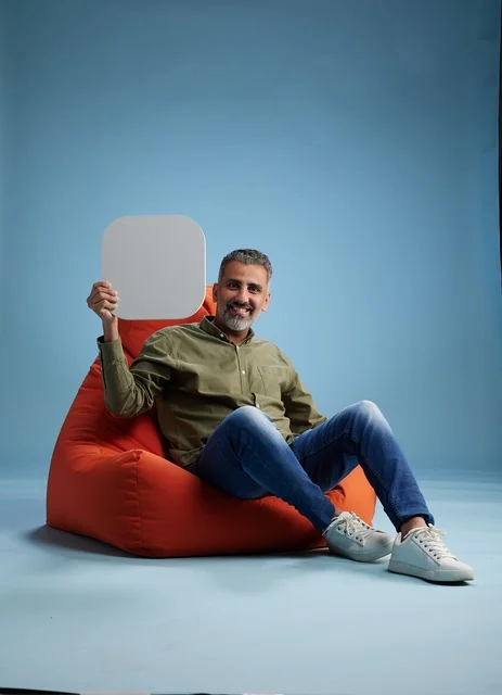 Saudi Man Holding Blank Sign While Sitting on Red Bean Bag
