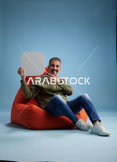 رجل سعودي يحمل لافتة فارغة على كرسي بين باج