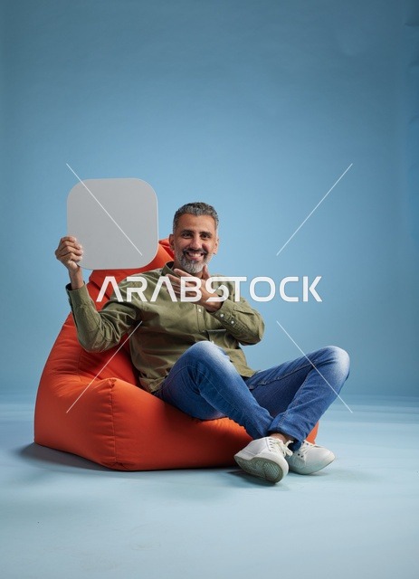 رجل سعودي يحمل لافتة فارغة على كرسي بين باج