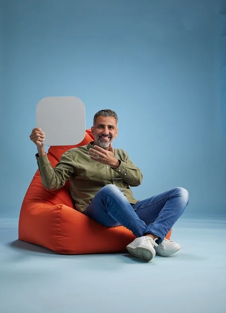 رجل سعودي يحمل لافتة فارغة على كرسي بين باج