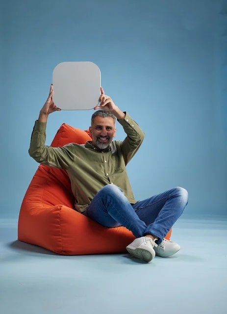 رجل سعودي يحمل لوحة بيضاء فارغة على مقعد مريح