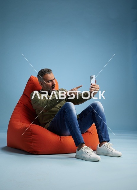 رجل سعودي يستخدم الهاتف الذكي جالسًا