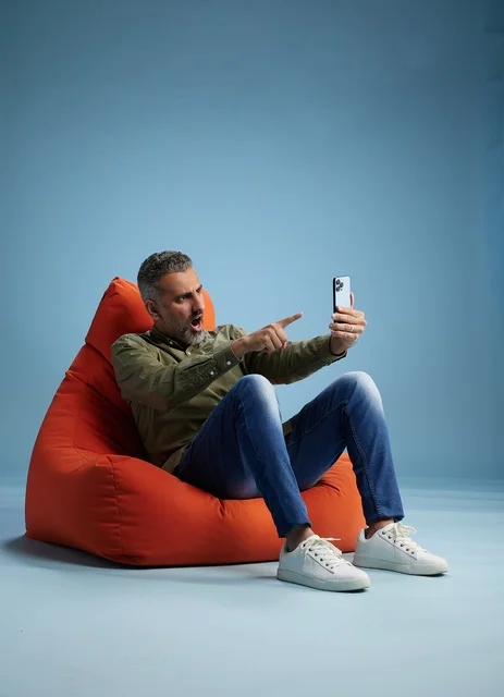 رجل سعودي يستخدم الهاتف الذكي جالسًا