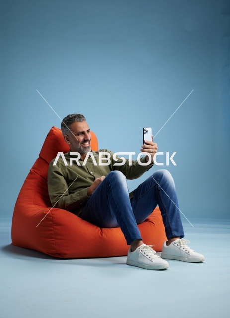 Saudi Man Using Smartphone on Bean Bag in Studio