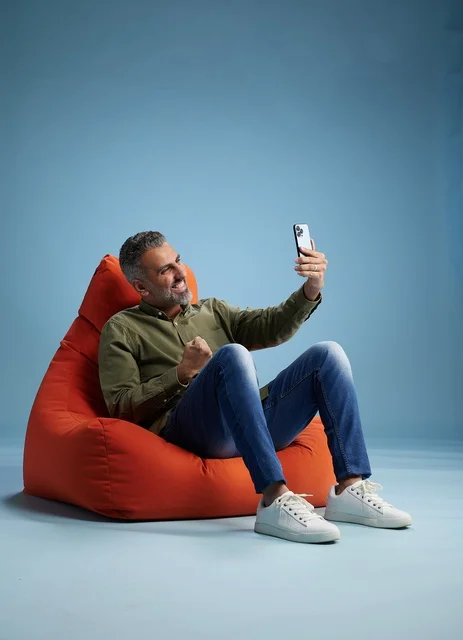 Saudi Man Celebrating on Smartphone in Bean Bag