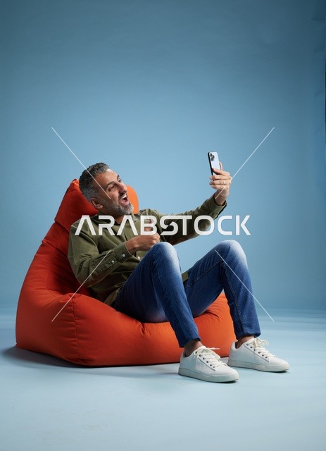 رجل سعودي على مقعد مريح يستخدم الهاتف الذكي