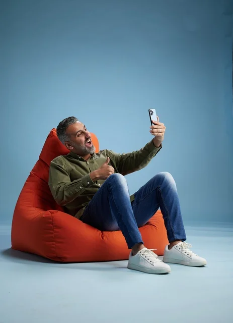 رجل سعودي على مقعد مريح يستخدم الهاتف الذكي