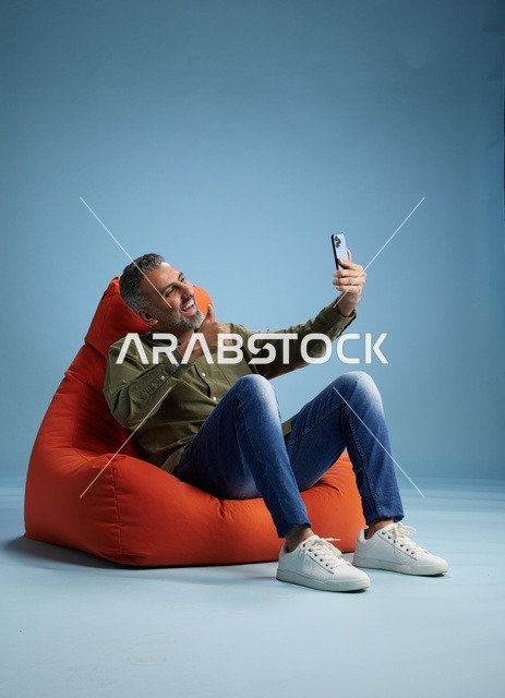 رجل سعودي على مقعد بين باج يستخدم الهاتف الذكي