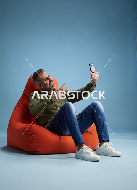 رجل سعودي يستخدم الهاتف الذكي على كرسي استرخاء