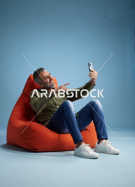 رجل سعودي على مقعد محشو يجري مكالمة فيديو بالهاتف