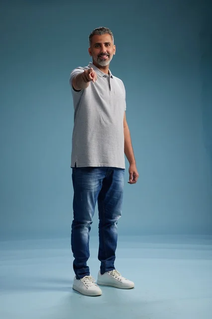 رجل سعودي يشير بإصبعه بملابس كاجوال في استوديو تصوير