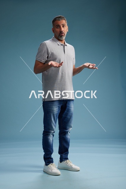 رجل سعودي بملابس كاجوال يرفع يديه بحيرة