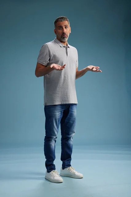 رجل سعودي بملابس كاجوال يرفع يديه بحيرة