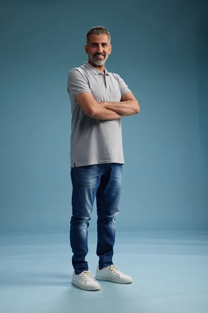 رجل سعودي بملابس كاجوال أمام خلفية زرقاء