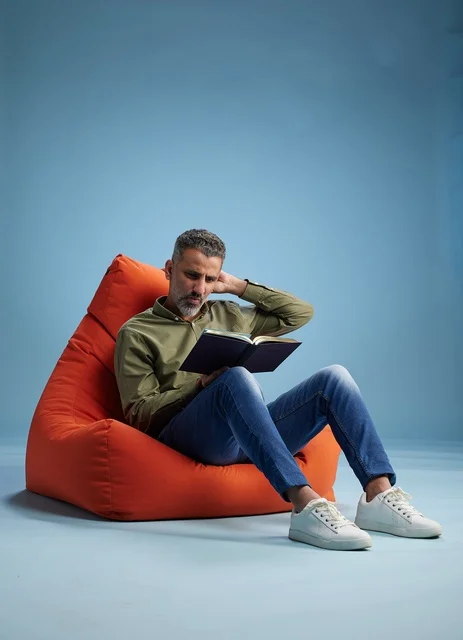 Saudi Man Reading Book on Orange Bean Bag