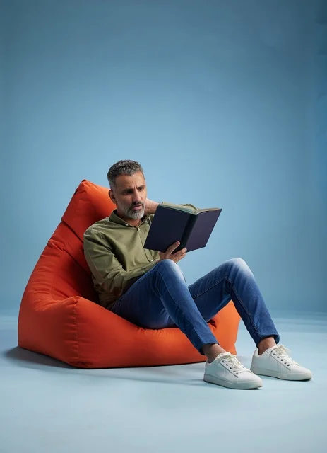 Saudi Man Reading Book on Orange Bean Bag