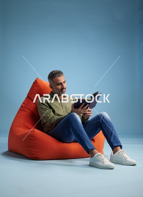 رجل سعودي يقرأ كتاباً على كنبة كيس