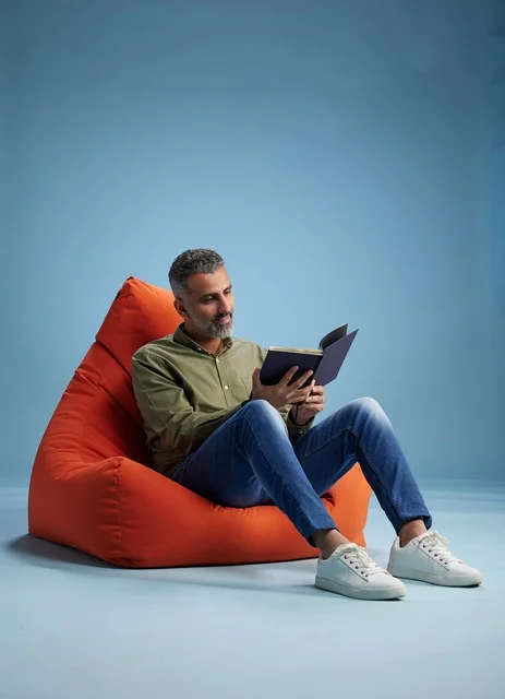 Saudi Man Reading Book on Orange Bean Bag