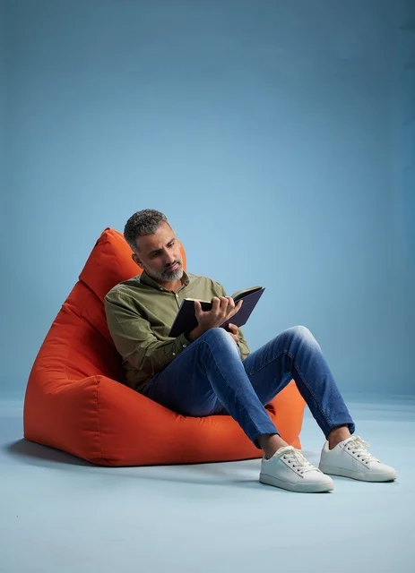 رجل سعودي يقرأ كتاباً على كنبة كيس حمراء