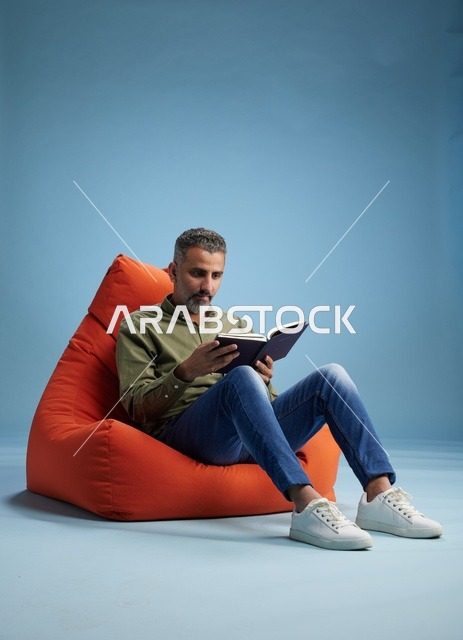 رجل سعودي يقرأ على كنبة كيس في الاستوديو