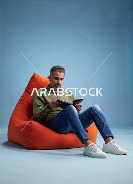 رجل سعودي يقرأ كتابًا على كنبة كيس