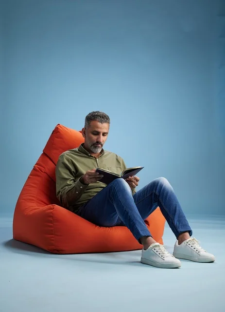 Saudi Man Reading Book on Orange Bean Bag