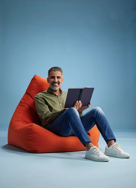 رجل سعودي يقرأ كتاباً على كنبة كيس برتقالية