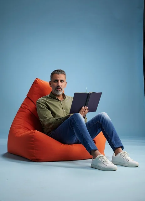 Saudi Man Reading Book on Orange Beanbag Chair