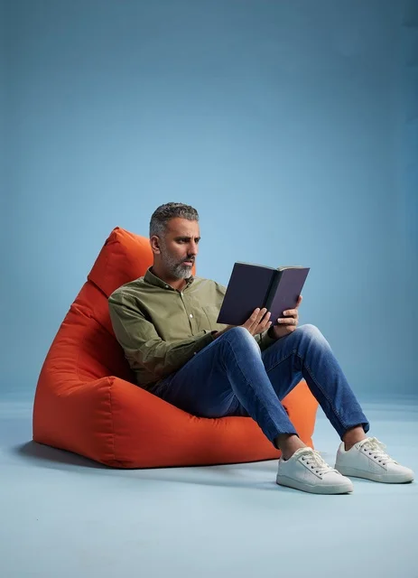 رجل سعودي يقرأ كتابًا على كنبة كيس