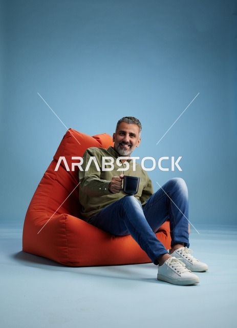 رجل سعودي جالس على كنبة كيس مع فنجان قهوة